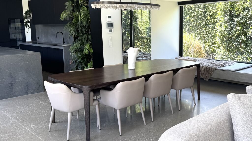 Modern dining area with bespoke table, neutral seating, and open-plan interior design
